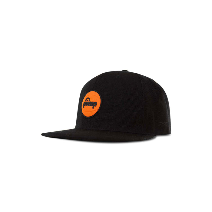 The Reebok Pump Hat by Reebok is a black flat-brim cap with an orange circular patch reading "pump" in lowercase black letters on the front, displayed against a white background.