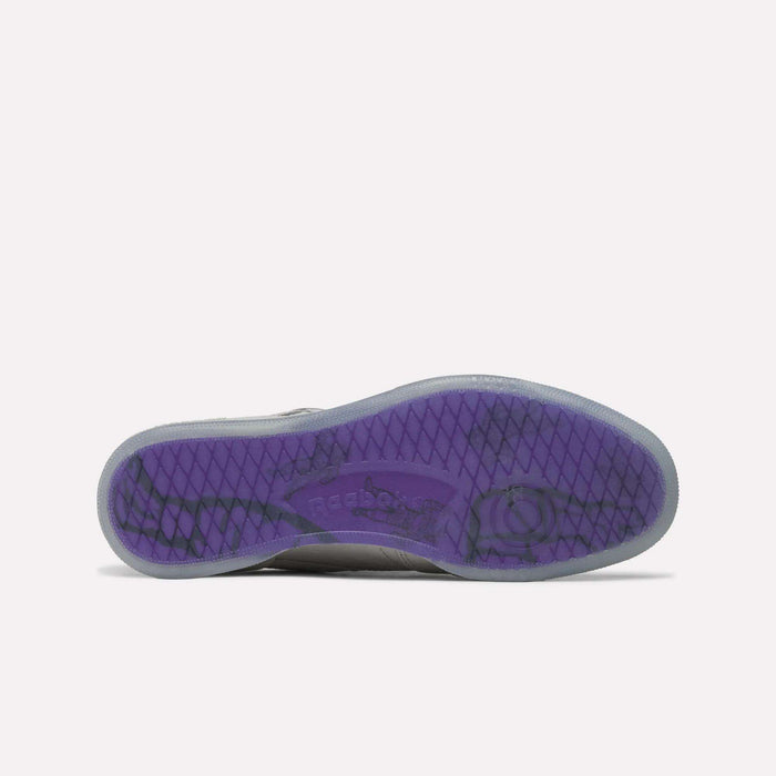 The image features the purple, translucent sole of the Reebok x BBC Club C 85 Shoes, showcasing a diamond-patterned tread and central Reebok branding that highlights this iconic tennis silhouette from Reebok.