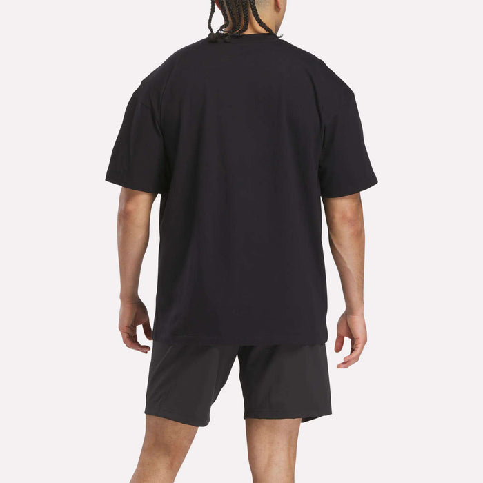 A person with braided hair, seen from behind, wears a Reebok x F45 Training Relaxed T-Shirt and black shorts against a plain light background.