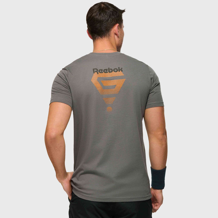 A man faces away, wearing the Reebok x GLDN PNT Jersey Tee by Reebok, featuring an orange geometric design and logo on the back. Paired with black shorts and wristband, it's a minimalist choice for everyday wear.