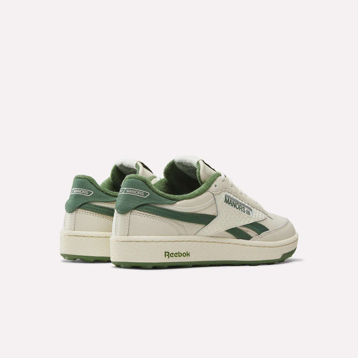 The Reebok x Manors Club C Revenge Golf Shoes, featuring off-white and green color accents and MANORS branding on the side, are displayed from an angled rear and side view against a plain white background.