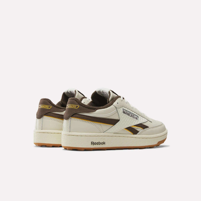 A pair of Reebok x Manors Club C Revenge Golf Shoes in beige with brown and yellow accents, showcasing MANORS branding and a gum sole, displayed on a white background.