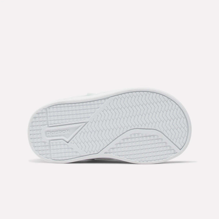 The image shows the white rubber sole of Reebok Kids' Royal Prime Snug Shoes for babies and toddlers, with zigzag and grid treads for grip. The Reebok logo is embossed on the left side of the sole.