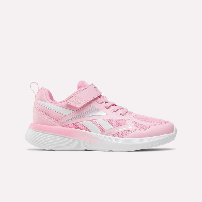 The Reebok Rush Runner 6.0 Elastic Lace Top Strap Running Shoes for little kids in Expressive Pink/Ftwr White feature a mesh and synthetic upper, hook-and-loop strap, elastic laces, and a white sole, shown in side profile on a white background.