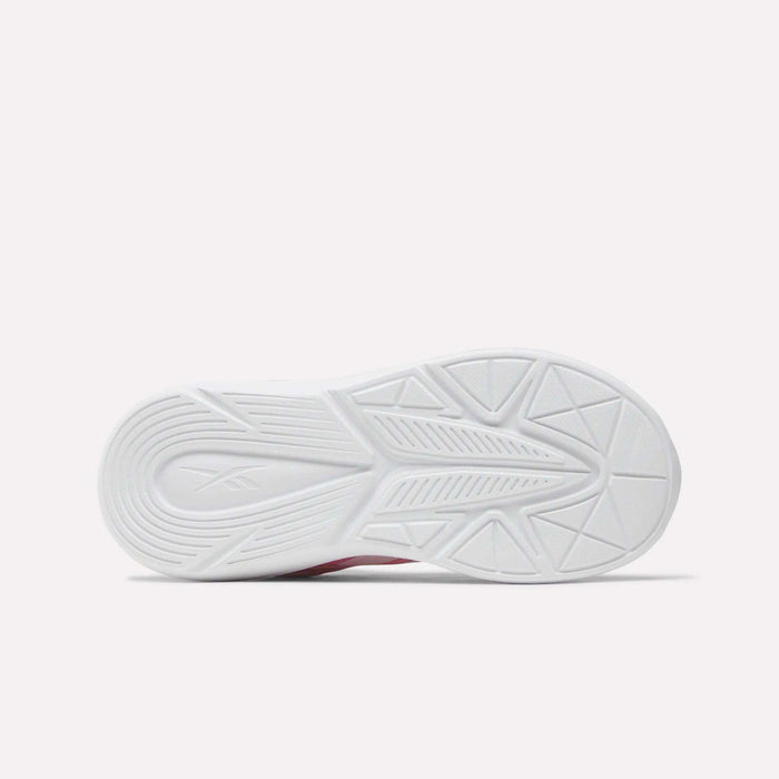 The image shows the bottom view of a white Reebok Rush Runner 6.0 Elastic Lace Top Strap Running Shoe sole for little kids, featuring a textured pattern with grooves, lines, and geometric shapes on a plain light background.