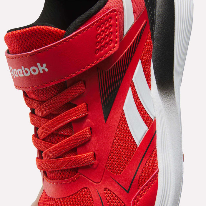 Close-up of Reebok Rush Runner 6.0 Elastic Lace Top Strap Running Shoes for little kids in red, with white and black accents, mesh texture, elastic laces, a velcro top strap, and Reebok branding on the strap and side.