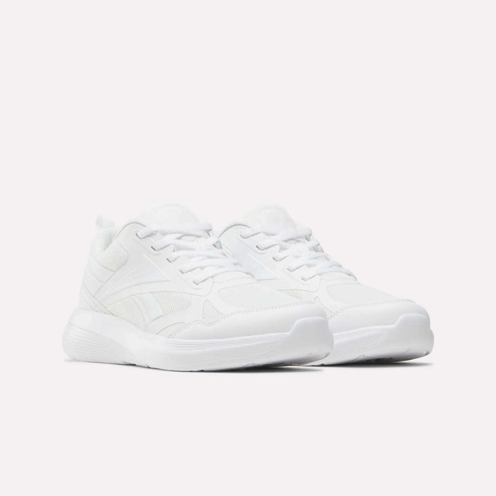 A pair of all-white Reebok Rush Runner 6.0 Running Shoes for big kids, featuring laces, mesh, and synthetic material, displayed on a plain white background.