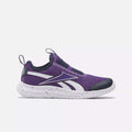 The Reebok Rush Runner Slip-On Shoes for little kids feature Vector Navy, Dynamic Purple, and white colors, a mesh upper, white sole and accents, black toe and heel caps, and a pull tab—perfect stylish running shoes for girls. Displayed on a light background.