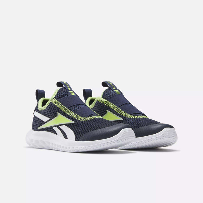 The Reebok Rush Runner Slip-On Shoes for little kids feature a navy blue design with white soles, neon yellow accents, and side logos. Lightweight cushioning ensures comfort. Shown on a white background.