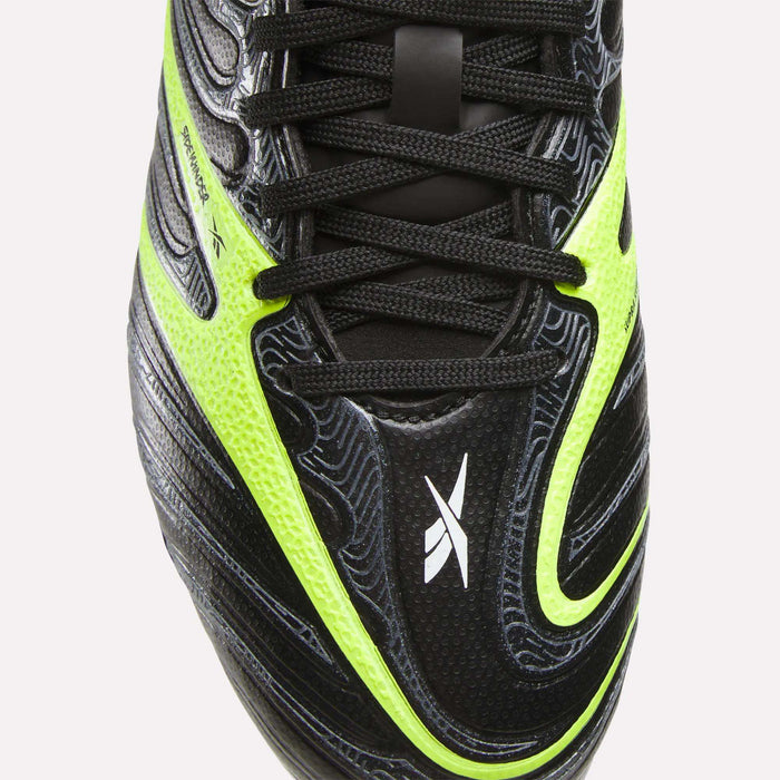 Close-up of the upper part of Reebok Sidewinder 26 League FG Cleats for big kids, featuring black color with neon yellow and white accents, black laces, textured surface, firm ground studs, and a small white X-shaped logo on the toe.