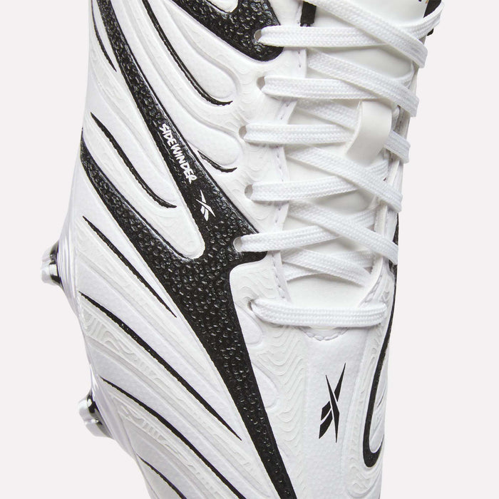 Close-up of the Reebok Sidewinder 26 League Firm Ground Cleats for Big Kids in white, featuring black textured details with dynamic black lines, visible laces and part of the sole. The design includes firm ground studs for optimal traction and a small Dreammaker label on the side.