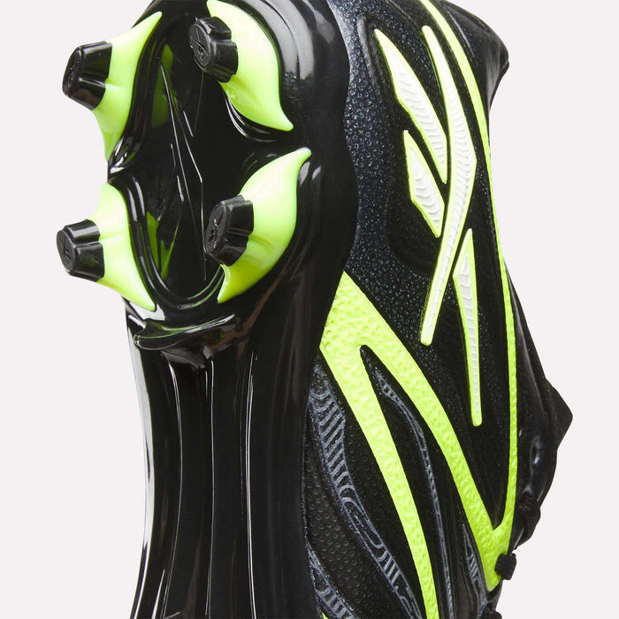 Close-up of the sole of Reebok Sidewinder 26 League FG Cleats for big kids in black and neon yellow, showing textured material and firm ground studs designed for excellent traction.