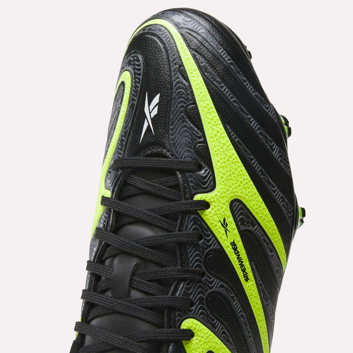 Close-up of Reebok Sidewinder 26 League Firm Ground Soccer Cleats in black with neon yellow-green accents, textured detailing for ball control, black laces, a white Reebok logo on the side, and firm ground studs for traction.