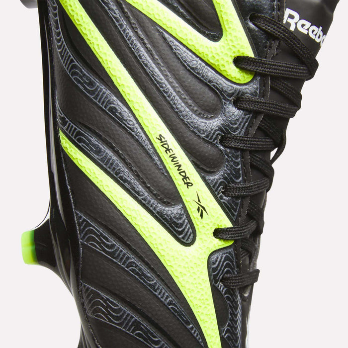 Close-up of a black Reebok Sidewinder 26 Pro FG Cleat with neon yellow accents and textured patterns, designed for firm ground play and improved ball control.