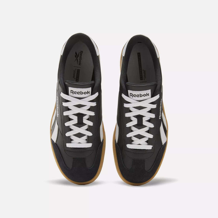 Top view of Reebok Smash Edge Shoes in black, featuring white laces, white side stripes, and brown rubber soles. These minimalist sneakers are positioned side by side on a plain white background.