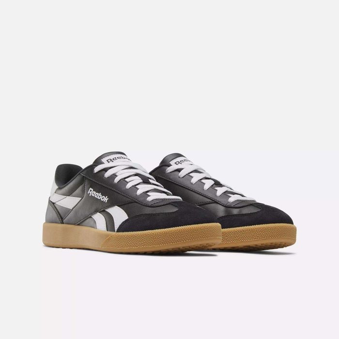 The Reebok Smash Edge Shoes are black and white with gum rubber soles, white laces, and Reebok logos on the sides and tongues, displayed on a plain white background for a clean, minimalist look.