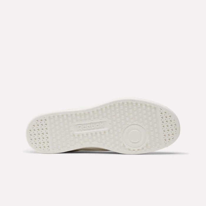 This image displays the white, textured rubber sole of Reebok's Smash Edge Shoes from below, highlighting small triangular patterns, circular tread details, and an embossed Reebok logo in the center.