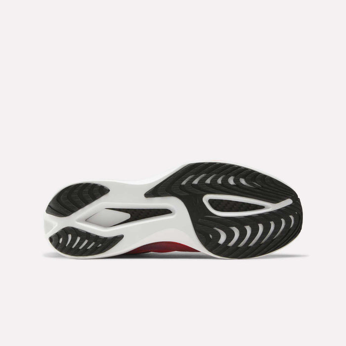 The image displays the outsole of the Reebok SpeedShifter Running Shoes, featuring a white base with black rubber traction patterns and striking red accents along the sides. Subtle carbon fiber detailing is integrated into the design, boosting both durability and performance.
