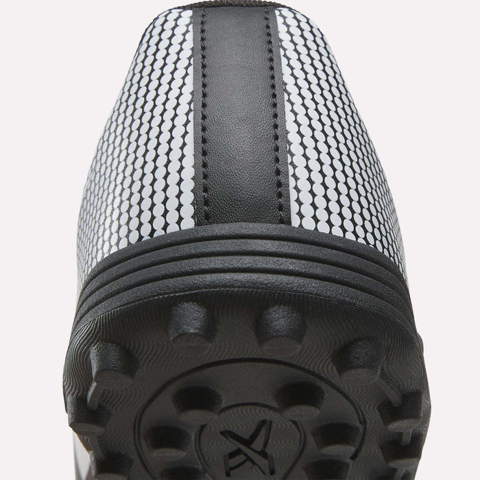 Close-up view of the heel and sole of the Reebok Strike Turf Soccer Shoes, showcasing textured rubber studs, a central black stripe, and a white upper patterned with small black circles—ideal as practice soccer shoes.