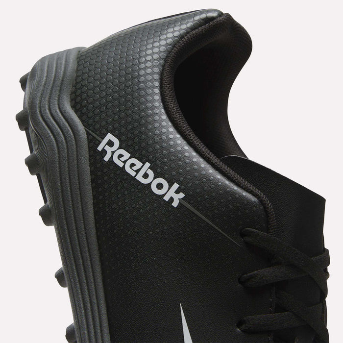 Close-up of a black Reebok Strike Turf Soccer Shoe featuring textured dots, a silver Reebok logo, and a gray cleated sole—ideal for soccer practice. Only part of the shoe and its laces are shown.