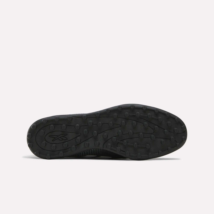 Black rubber sole featuring a textured tread pattern with small round bumps, displayed against a plain light background. Designed for the Reebok Strike Turf Soccer Shoes, this sole is perfect for soccer practice. A small Reebok logo appears on the left side of the sole.