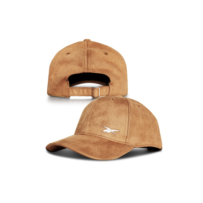 The Suede Badge Cap by Reebok features a white embroidered logo on the front left panel and an adjustable strap with a metal buckle at the back. Made from premium vegan suede, it offers both style and comfort.