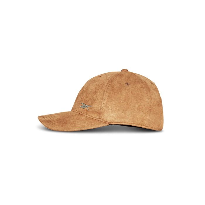 The Suede Badge Cap by Reebok is a tan vegan suede cap with a small embroidered Reebok logo on the side, displayed against a plain white background.