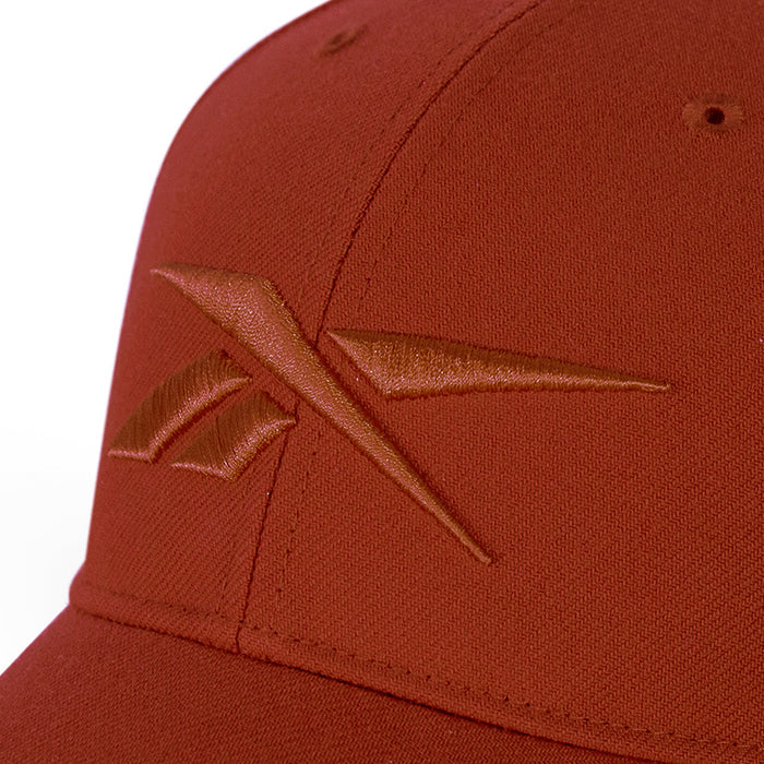 A close-up of a rust-colored Reebok Vector Baseball Cap showcases the embroidered front logo and adjustable snapback closure for a perfect fit.