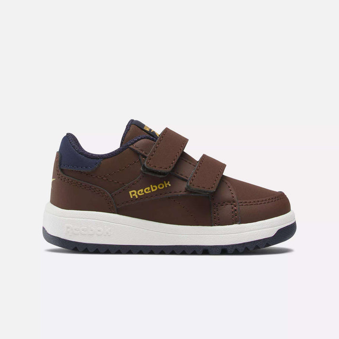 The Weebok Clasp Low Shoes by Reebok feature a brown design with navy accents, a Velcro strap, white sole, and gold Reebok logo—perfect for infants and toddlers’ daily wear. Shown on a white background.