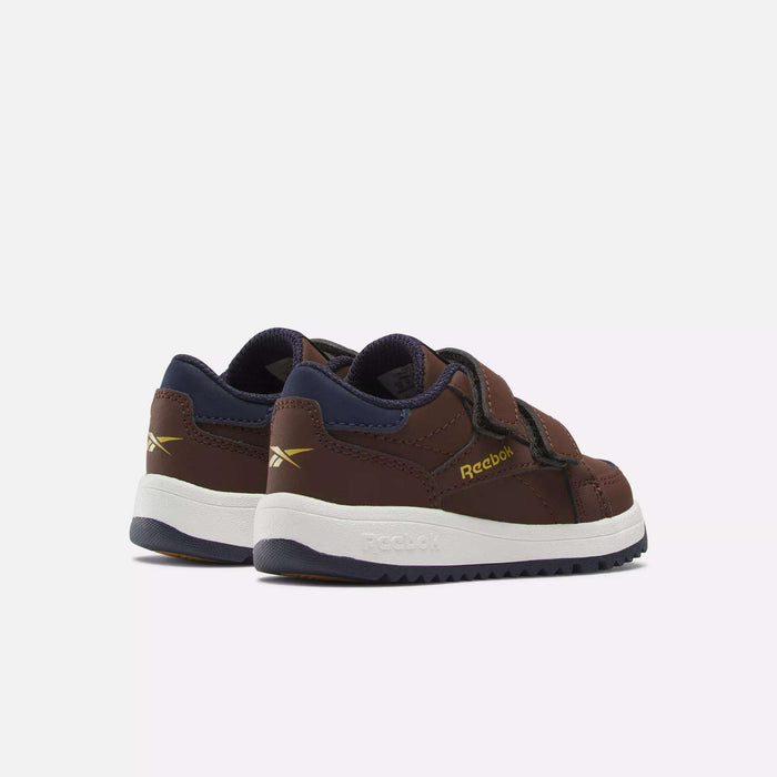 The Reebok Weebok Clasp Low Shoes for infants and toddlers in brown, with navy blue and gold accents, feature a Velcro strap closure and white rubber soles, shown against a plain white background.
