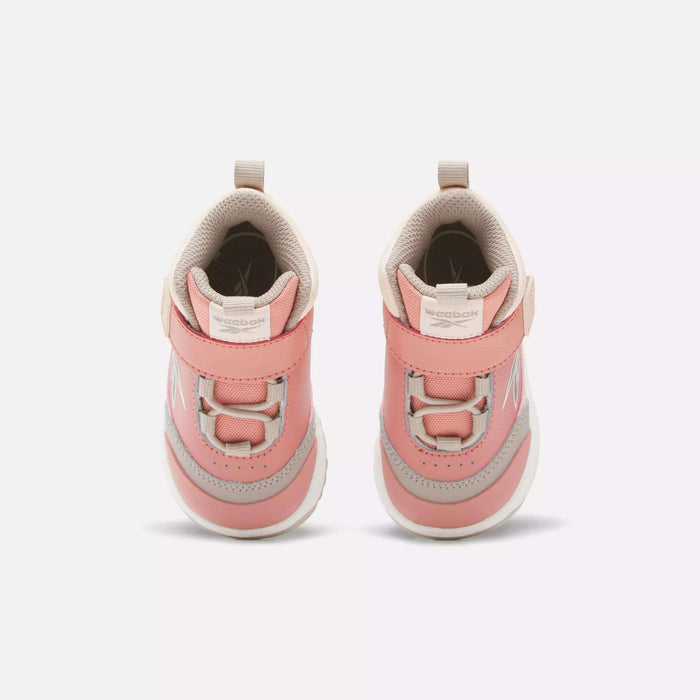 A pair of pink and beige Reebok Weebok Storm X Shoes for infants and toddlers, featuring velcro straps, shown from above on a plain white background.