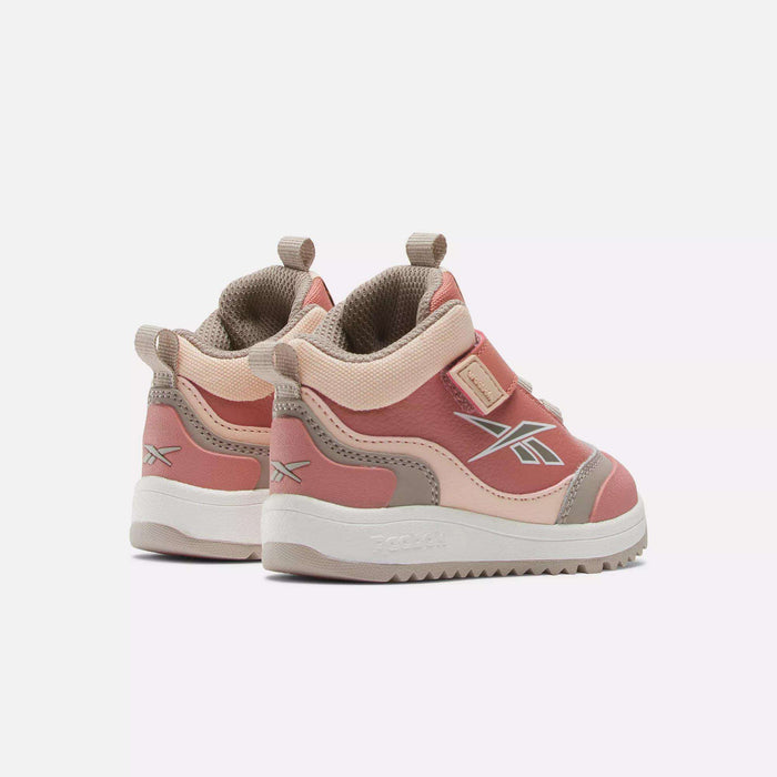 A pair of Reebok Weebok Storm X Shoes for infants and toddlers in pink and beige, featuring velcro straps and side Reebok logos, displayed on a plain white background.