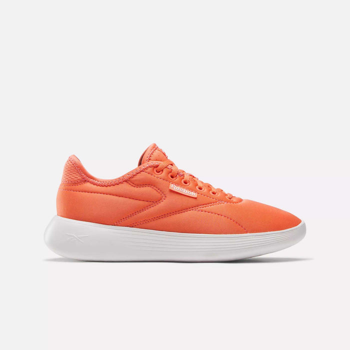 The Reebok Women's Active Lite Shoes feature a bright orange design, matching laces, DMX technology, and a thick white sole. Shown from the side on a plain white background.