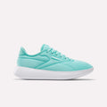 The Reebok Women's Active Lite Shoes feature a light teal upper, white sole, low-top silhouette, and DMX technology for comfort. The minimalist sneaker displays the Reebok logo near the laces and is shown in a side view against a white background.