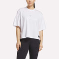 A woman stands against a light background in a loose-fitting Reebok Women's Basketball Mesh T-Shirt with a small chest logo and black leggings.