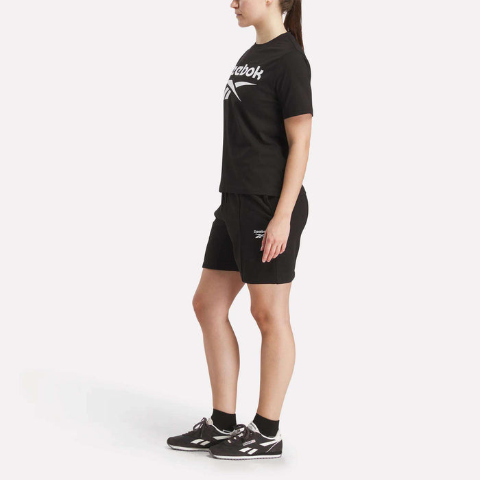 A woman in black shorts wears a Reebok Women's Big Logo Crewneck Short Sleeve Tee.