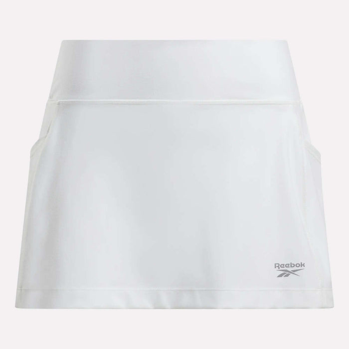 The Women's Break Point Skort by Reebok is plain white with a high waistband, two side pockets, built-in compression shorts, and a small gray Reebok logo near the right hem.