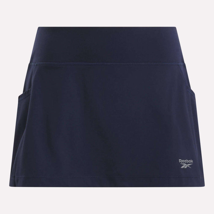 The Women's Break Point Skort by Reebok is a navy blue training skort featuring side pockets, built-in compression shorts, and a small logo on the lower right, shown against a light background.