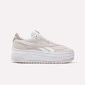 A side view of Reebok Women's Campio Extra Shoes in beige and white, featuring a thick white platform sole, white laces, and Reebok logos on the side and heel, set against a plain white background.