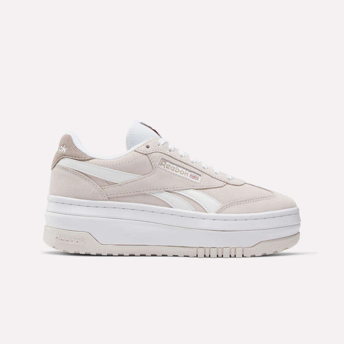 A side view of Reebok Women's Campio Extra Shoes in beige and white, featuring a thick white platform sole, white laces, and Reebok logos on the side and heel, set against a plain white background.