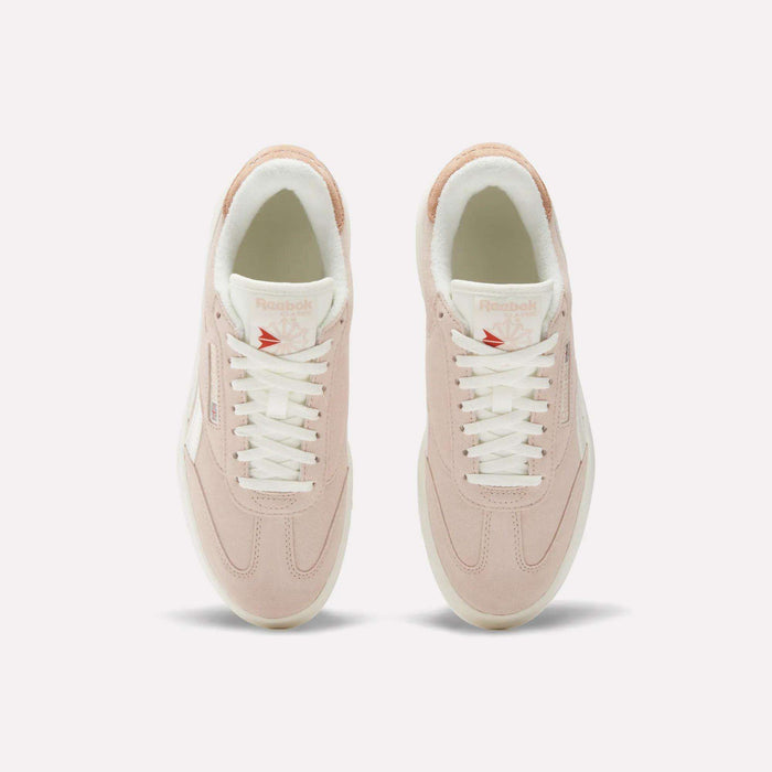 Top view of a pair of Reebok Women's Campio Extra Shoes in light pink with white laces, white soles, and subtle branding on the tongue and side, displayed on a plain white background.