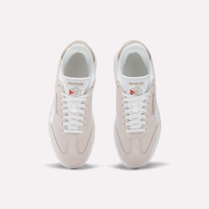 Top view of a pair of Women's Campio Extra Shoes by Reebok in light beige with white laces and soles, featuring Reebok branding on the tongue and side, placed side by side on a plain light background.
