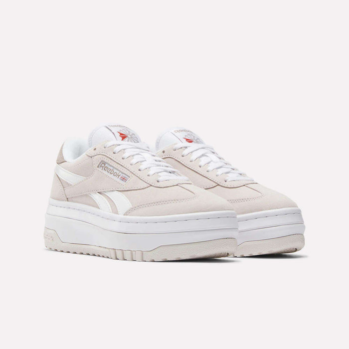 A pair of Women's Campio Extra Shoes by Reebok in beige, featuring white accents, thick white soles, white laces, and the Reebok logo on the sides and tongue, displayed on a plain white background.
