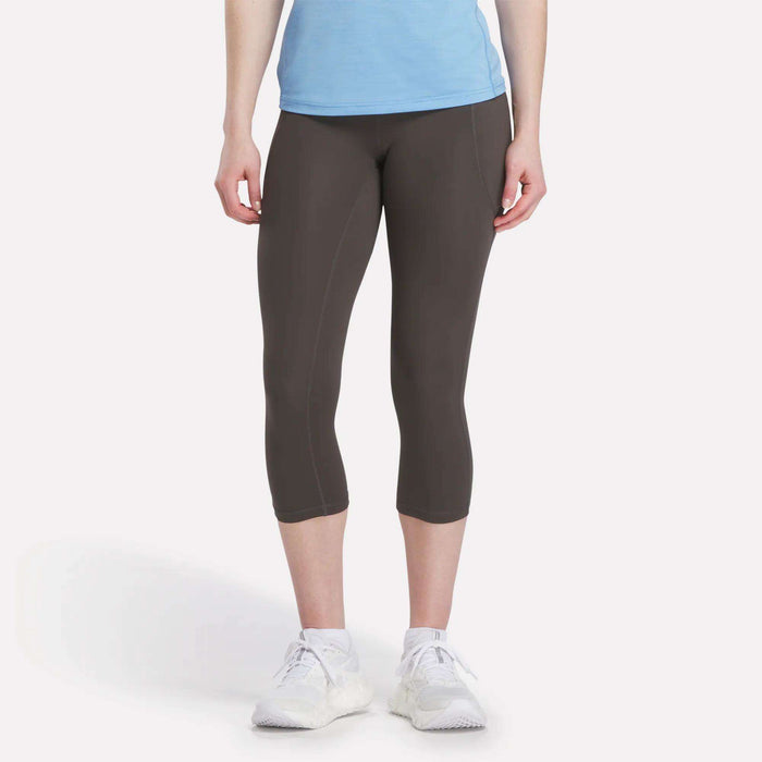 A woman models Reebok Women's Capri Leggings, shown from the waist down against a plain white background.
