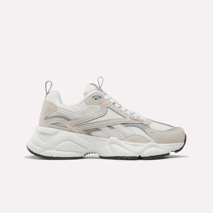 The Reebok Women’s Charge Shoes in White/Beige feature a chunky sole, mesh and suede panels, and a lace-up design. Shown in side profile against a plain light background, they are an ideal choice for anyone seeking stylish women’s athletic footwear.