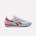 The Reebok Women's Classic AZ Shoes feature a light blue upper, red accents, white sole, and black tread in a retro running-inspired design, shown in side profile on a plain white background.