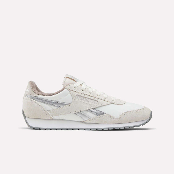 The Reebok Women's Classic AZ Shoes feature a white and beige colorway with silver accents, vintage details, low-top design, lace-up closure, and rubber sole—making them a stylish addition to any women’s sneaker collection. Shown on a white background.