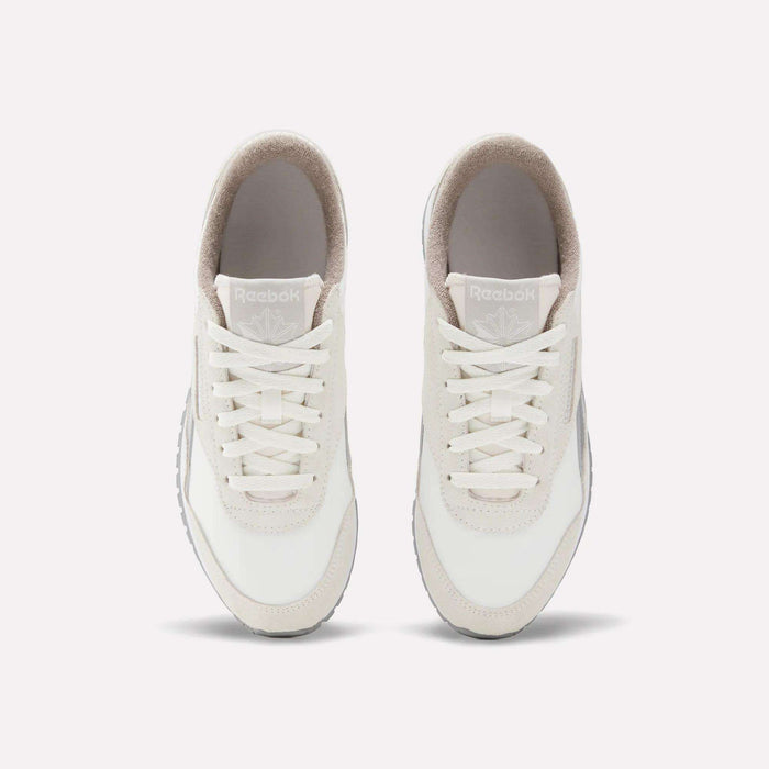 The Reebok Women's Classic AZ Shoes, in white with beige accents, are shown from above with visible laces, tongue, and Reebok branding. These vintage-style sneakers are placed side by side on a plain light background.