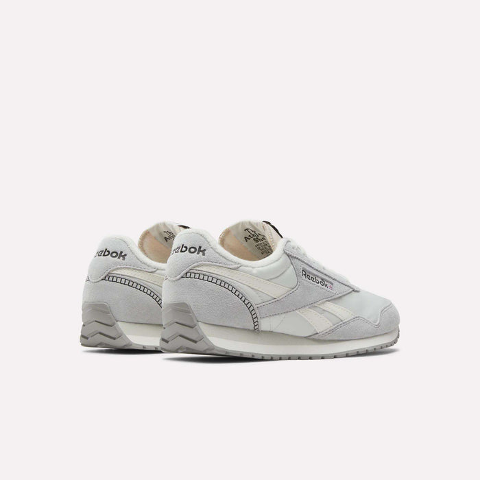 The Reebok Women's Classic AZ Shoes feature light gray and white suede and leather panels, a side logo, and gray soles in a low-profile design, shown angled on a plain white background.