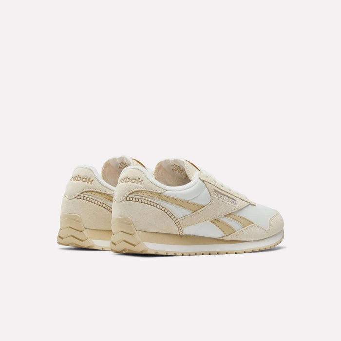 The Reebok Women's Classic AZ Shoes in beige and white, featuring suede and leather accents, are displayed on a plain white background at an angle to highlight the low-profile design and showcase both side and back details.